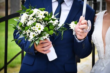 Groom holding a bridal bouquet and umbrella