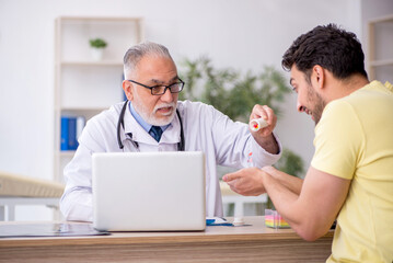Fototapeta premium Young male patient visiting old male doctor