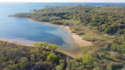 Aerial view a secondary point or hump surrounding by lush green trees and curved sandy shoreline at Isle du Bois Ray Roberts Lake State Park, remote primitive camping sites - obrazy, fototapety, plakaty