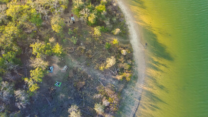 Curved shoreline and remote waterfront primitive camping sites with tents at Isle du Bois Ray Roberts Lake State Park lush green tree forest near Denton, Texas, US aerial view - obrazy, fototapety, plakaty