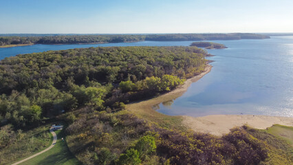 Aerial view a secondary point or hump surrounding by lush green trees and curved sandy shoreline at...