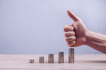 Stack of coins in ascending order. The finger up indicates the direction of capital growth of the interest deposit economy. Rate increase. Growth of shares and investments.