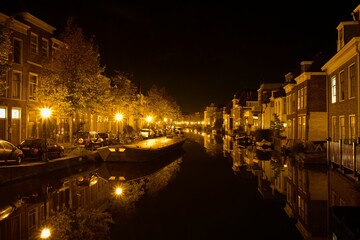 Fototapeta na wymiar Fleet of boats in a canal in front of a picturesque row of houses at night: Leiden