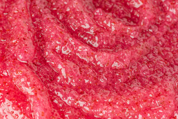 body scrub texture background. Red color exfoliating skincare product smear smudge swatch. Gentle creamy scrub cleanser strokes closeup