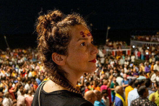Woman at night in Varanasi watching the Ganga Aarti ritual with many people in Varanasi in India
