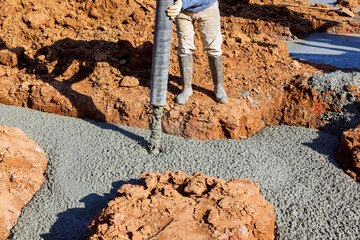Worker at construction site pouring spreading concrete mix new house foundation