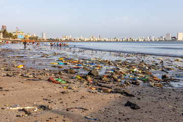 The sprawling Chowpatty Beach in Bombay, India, with people and all their trash and buildings in...