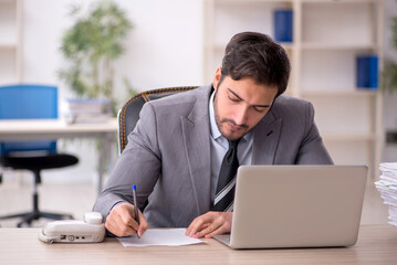 Young male employee and too much work in the office