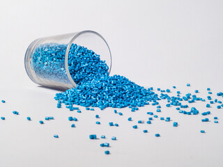 cold cut type blue pearlish masterbatch granules with glass cup in white background photo. This...