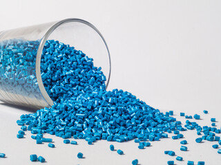 cold cut type blue pearlish masterbatch granules with glass cup in white background photo. This...