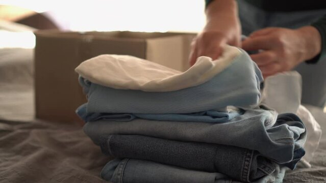 Concept of recycling clothes. Woman donates her clothes. Sale of used clothes. Moving to a new house, putting things in boxes