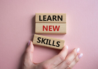 Learn new skills symbol. Concept words Learn new skills on wooden blocks. Beautiful pink background. Businessman hand. Business and Learn new skills concept. Copy space.