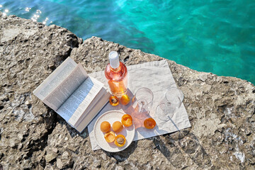 Two glasses of wine and summer fruits on the beach, sea and landscape in the background, summer picnic, travel, vacation, weekend getaway outdoors