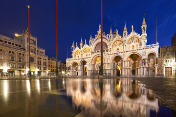 Basilica in San Marco square in Venice with aqua alta reflection at twilight.