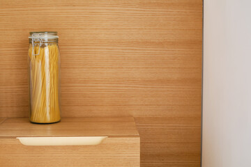 Assortment of cereals and pasta in glass jars on a wooden table. Kitchen storage concept