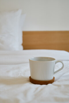 White cup with coffee or tea on the bed. Cozy morning photo. The concept is cozy and warm. Place for text
