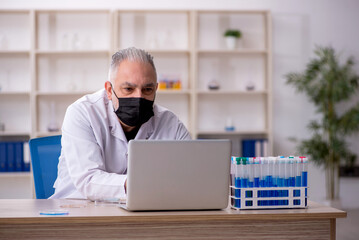 Old male chemist working at the lab