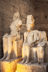 Night photo of damaged statue of the god Amun-Re and his wife Mut in Luxor Temple, Egypt. ...