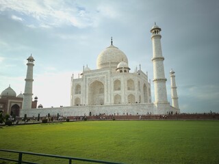 Fototapeta na wymiar Iconic Taj Mahal in India, with a lush green field and a crowd of people
