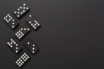 Black domino tiles on color background, top view
