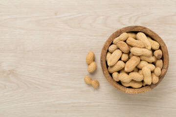 Unpeeled peanuts on wooden background, top view