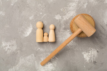 Wooden family figures with judge's gavel on concrete background,top view