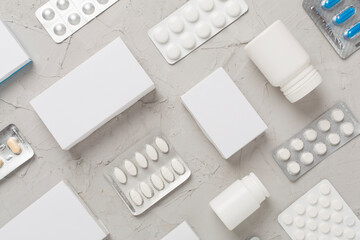 Flat lay with different pills in blister packaging and boxes and on concrete background