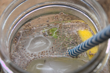 Chia seeds in a light brown bowl, metal spoon on a natural fiber blanket.