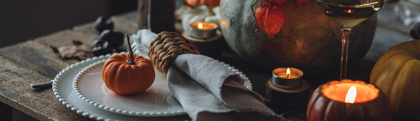 Atmospheric autumn elegant beautiful table setting with pumpkins for a wedding or thanksgiving family celebration. Fall decoration countryside rustic style, cozy home atmosphere , candles, wine banner