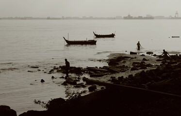 Grayscale shot of a shoreline of water, with several boats moored in the distance.