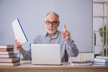 Old male teacher sitting in the classroom