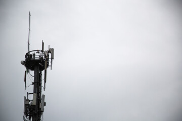 Grayscale of a cellular communication tower with numerous antennas and radio transmitters