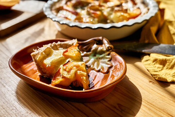 Autumn healthy eating. Slice of delicious seasonal tart with baked pumpkin, brie cheese and herbs in the plate a shape of pumpkin.