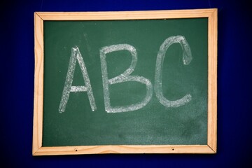 Fototapeta premium Close-up view of a chalkboard with a stylized ABC written in white chalk on the blackboard surface