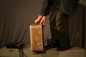 Male stands in front of a stage, displaying a piece of luggage in his hands next to a radio