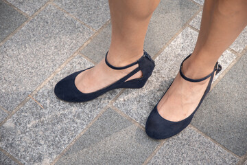beautiful female tanned legs in dark blue strappy shoes, retro fashion for walking around the city,...