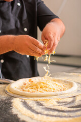 Pizza dough being prepared with cheese, tomato sauce, cheese