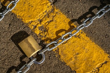 Yellow curb with two heavy chains securely held together with a padlock