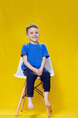 Positive boy in casual clothes sitting on chair