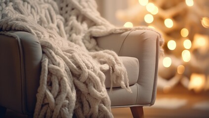 Cozy armchair with a knit blanket in a warm, festive room with a Christmas tree, ideal for holiday home decor ads. Perfect for interior design promotions or holiday home decoration inspiration.