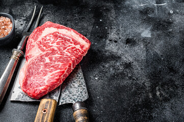 Butcher table with wagyu Rib Eye steak, raw  beef meat. Black background. Top view. Copy space