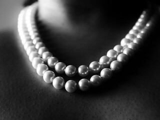 Close-up shot of a woman wearing a necklace of pearls around her neck in an artistic setting