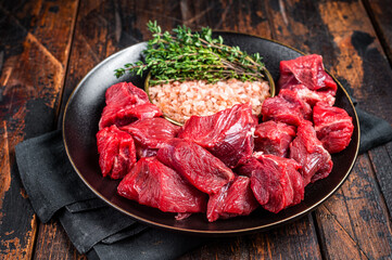Raw lean diced casserole beef meat for cooking Goulash. Wooden background. Top view