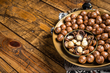 Organic Macadamia nuts in a shell ready to eat. Wooden background. Top view. Copy space