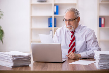 Obraz premium Old male employee and too much work in the office