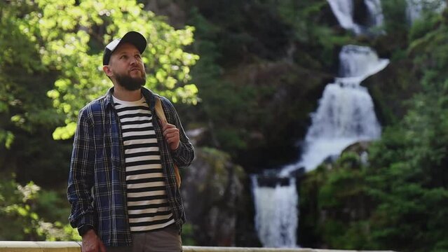 man admires a mountain landscape and a waterfall.