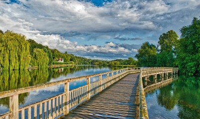 Wooden bridge over the River Thames surrounded by lush green trees