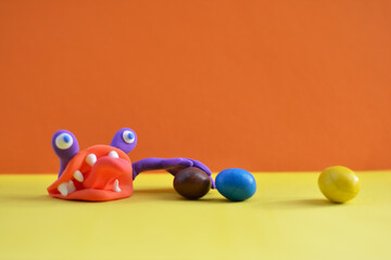 plasticine monster holds candy with his hands
