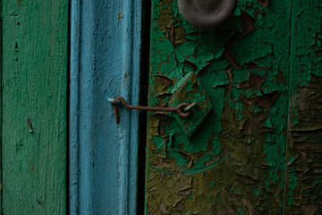 old door with flattened green and blue paint, which is closed with a metal lock