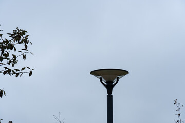 Close up of dark LED lamppost towards Grey sky and trees branches. Reidi tee, Tallinn, Estonia